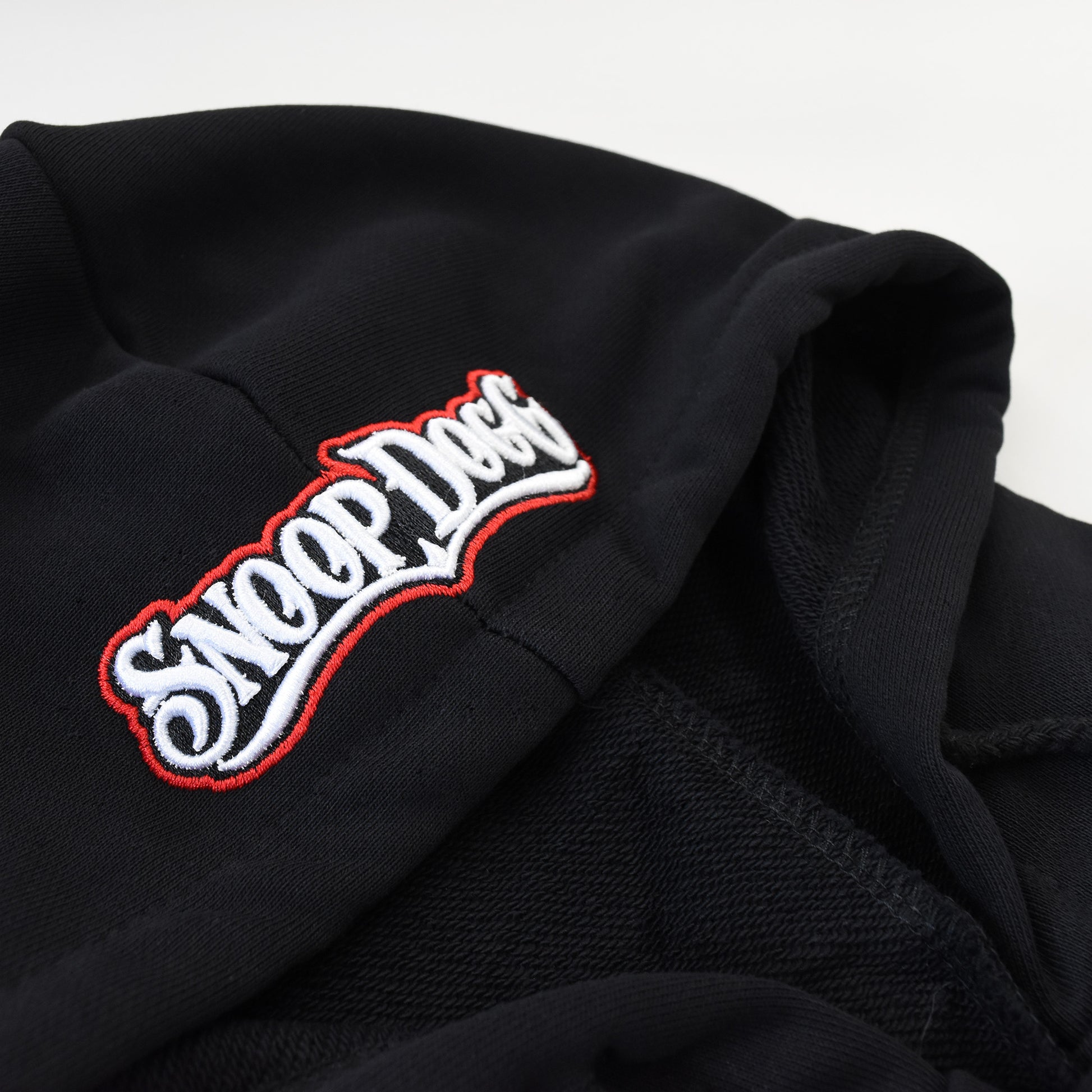 A close up detail image of the Snoop Dogg embroidered logo on the hood of the Mic Drop Deluxe Pet Hoodie.