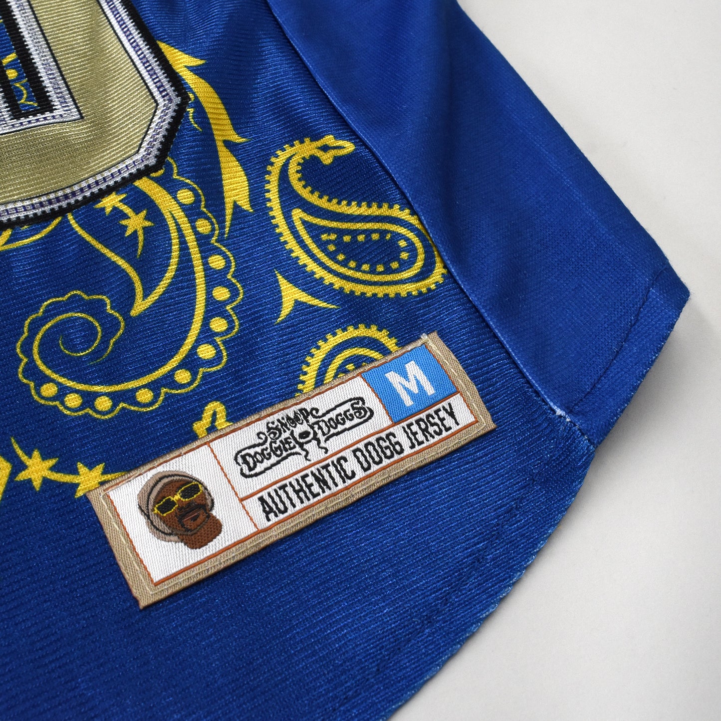 A close up detail image showing design sublimation, stretch fabric, and embroidered jersey tag of the Halftime Deluxe Pet Jersey.